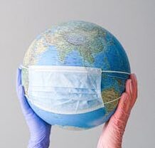 Hands in gloves holding a globe with a mask, symbolizing global health and pandemic protection.