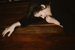 A woman in despair lying on a table next to a wedding ring, symbolizing heartache and divorce.