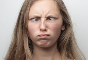 Close-up portrait of a girl with crossed eyes and a funny face indoors.
