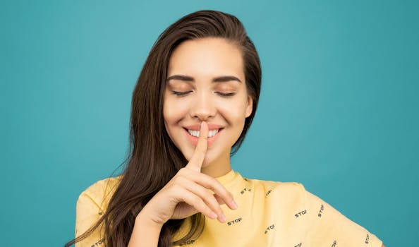 Charming woman with finger on lips, signaling silence against a teal background.